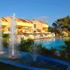 Una struttura con una piscina, circondata da lettini e ombrelloni, e una fontana in primo piano.