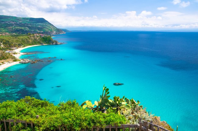Spiaggia con mare turchese e costa verde.