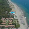 Vista aerea di una spiaggia con ombrelloni e complesso turistico.
