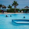 Persone nuotano in una piscina all'aperto vicino a ombrelloni e lettini.