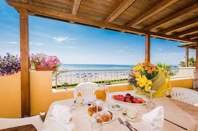 Vista mare da una terrazza con colazione imbandita.