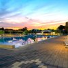 Piscina illuminata al tramonto con lettini disposti lungo il bordo.