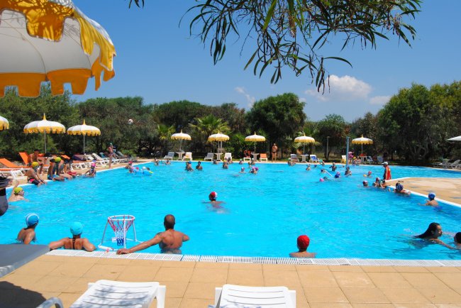 Persone in una piscina con ombrelloni gialli.