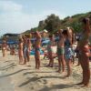 Persone in costume che fanno esercizi sulla spiaggia vicino al mare.