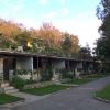 Complesso di bungalow con terrazze, circondato da alberi e giardini.