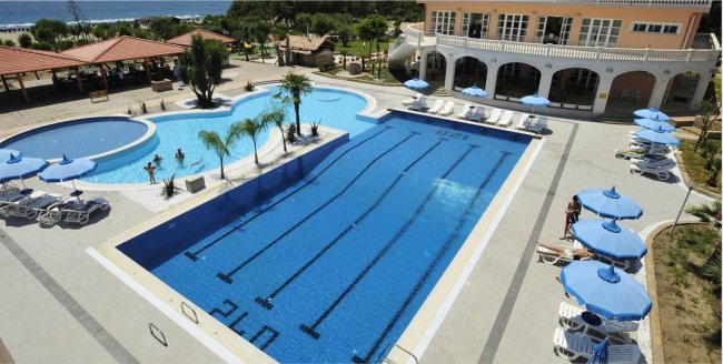 Piscina grande con ombrelloni blu e lettini.