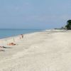 Spiaggia sabbiosa quasi deserta con alcune persone lontane.
