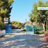 Ingresso con cancello blu e alberi intorno.