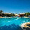 Piscina con ombrelloni e lettini blu sotto un cielo limpido.