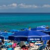 Spiaggia con ombrelloni blu, mare sullo sfondo.