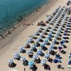 Spiaggia affollata con ombrelloni blu.