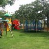 Parco giochi colorato con altalene e scivoli tra gli alberi.