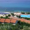 Spiaggia e villaggio con piscina vista dall'alto, ombrelloni disposti lungo la costa.