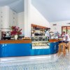 Interno di un bar con bancone blu, vetrina di dolci e due persone al bancone.