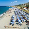 Spiaggia con lettini e ombrelloni blu e bianchi, persone che si godono il sole.