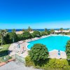 Una grande piscina all'aperto circondata da sdraio, ombrelloni e vegetazione rigogliosa.