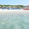 Spiaggia con ombrelloni giallo-blu e mare trasparente.