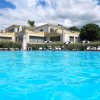 Piscina azzurra davanti a una villa con terrazze e lettini.