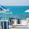 Sdraio e ombrelloni sulla spiaggia con mare azzurro.