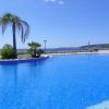 Spiaggia con piscina e palma, cielo azzurro sullo sfondo.