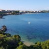 Una baia con acque azzurre e un piccolo promontorio verde.