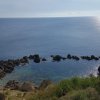 Una baia con rocce e mare calmo al tramonto.